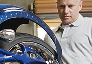 Man working on custom chrome rear wheel of metallic blue custom motorcycle