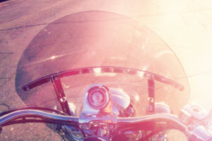 Motorcycle riding down the road into the sun