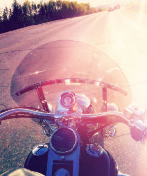 Motorcycle riding down the road into the sun