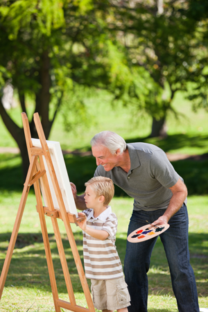 Grandfather and grandson painting at an easel outside