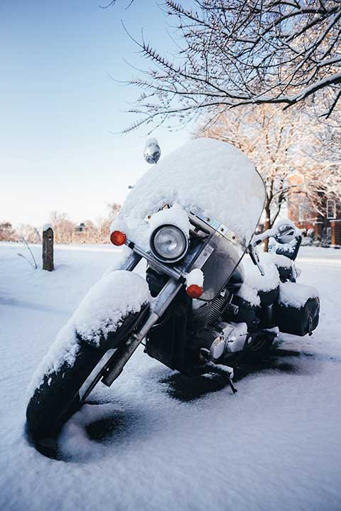 Motorcycle parked outside and covered in snow