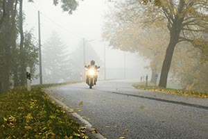 A motorcycle rider driving in a light fog