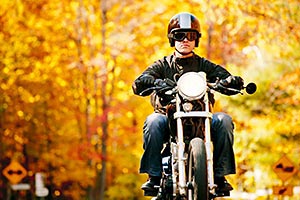 Motorcycle riding down road with leaves and fall colors in the background