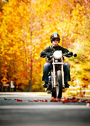 A biker riding through fall leaves on road